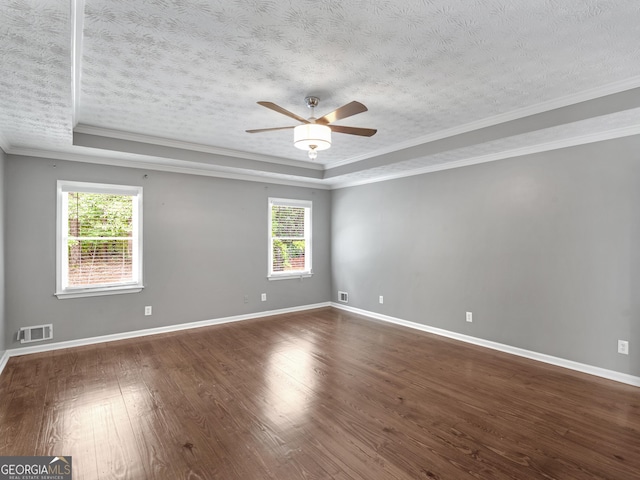 spare room featuring a raised ceiling, crown molding, dark hardwood / wood-style floors, ceiling fan, and a textured ceiling