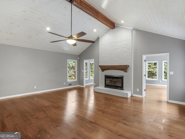 unfurnished living room with a fireplace, beam ceiling, a wealth of natural light, and hardwood / wood-style floors