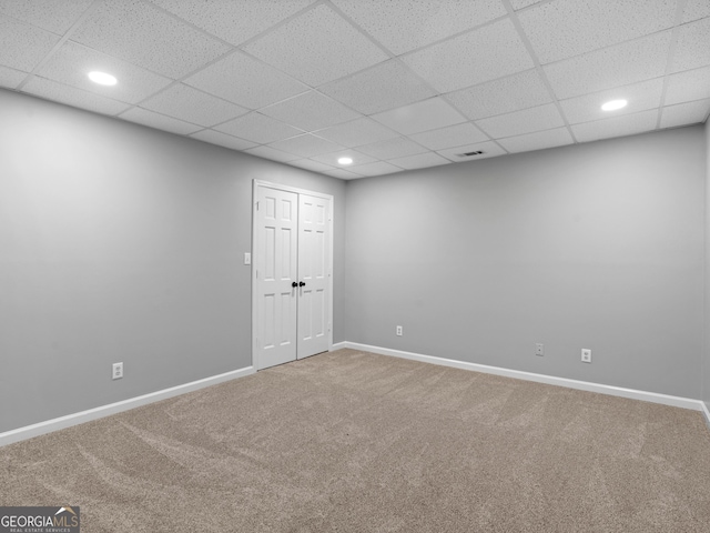 carpeted empty room with a drop ceiling