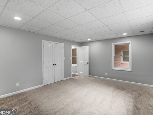 unfurnished room with carpet flooring and a drop ceiling