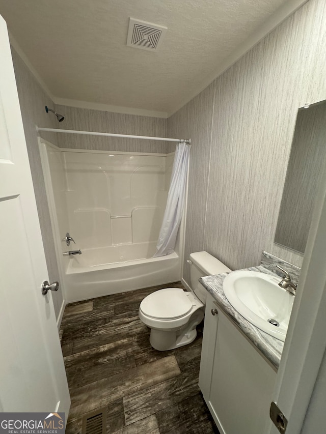 full bathroom featuring a textured ceiling, vanity, toilet, hardwood / wood-style flooring, and shower / bath combo with shower curtain