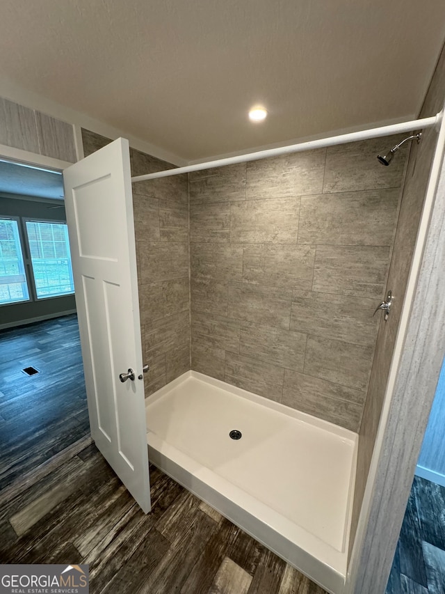 bathroom with tiled shower and wood-type flooring