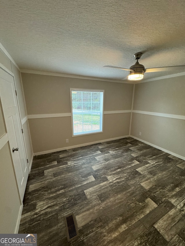 unfurnished room with ceiling fan, dark hardwood / wood-style floors, ornamental molding, and a textured ceiling