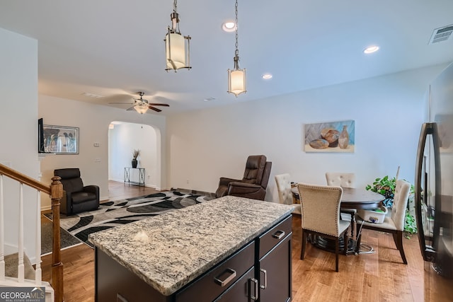 kitchen with a center island, decorative light fixtures, light hardwood / wood-style floors, stainless steel refrigerator, and ceiling fan