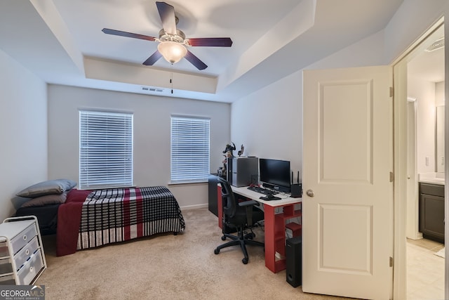 carpeted bedroom featuring ceiling fan, ensuite bath, and a tray ceiling