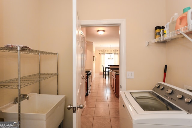 clothes washing area featuring an inviting chandelier, washer / clothes dryer, and light tile patterned flooring