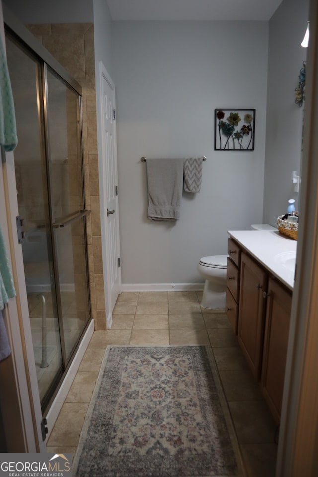 bathroom with tile patterned flooring, vanity, toilet, and a shower with shower door