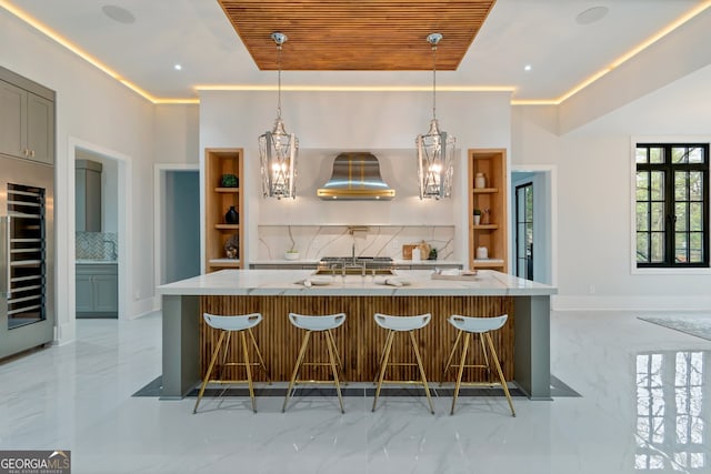 kitchen with a spacious island, beverage cooler, backsplash, hanging light fixtures, and ventilation hood