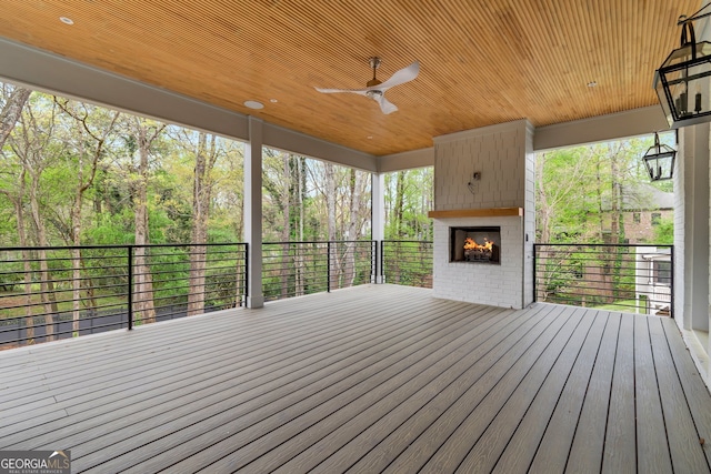 wooden terrace with a large fireplace and ceiling fan