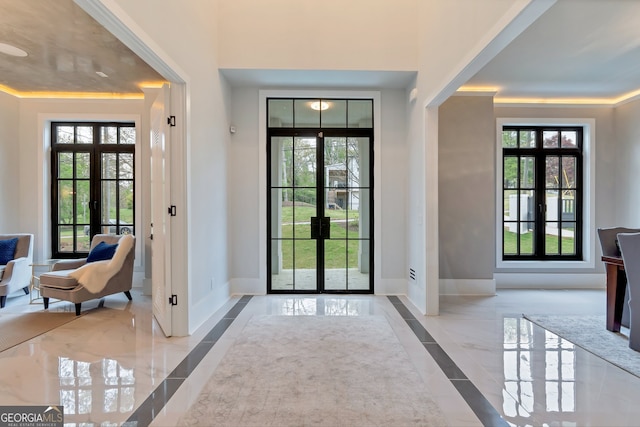 entryway with a healthy amount of sunlight, crown molding, and french doors