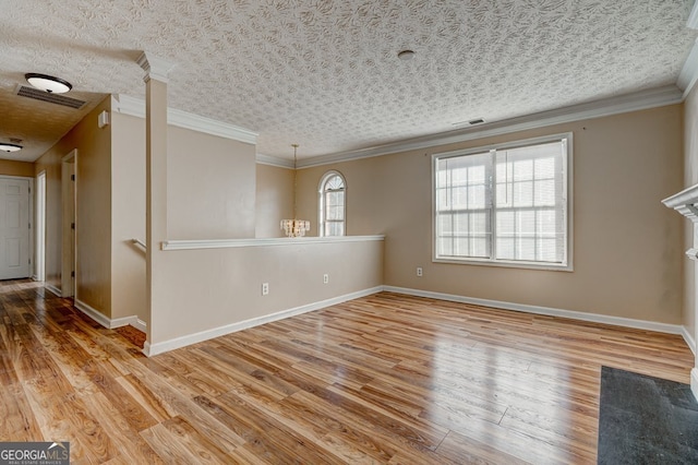 empty room featuring hardwood / wood-style flooring, crown molding, a textured ceiling, and ornate columns