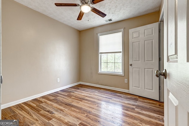 empty room with ceiling fan, light hardwood / wood-style flooring, and a textured ceiling