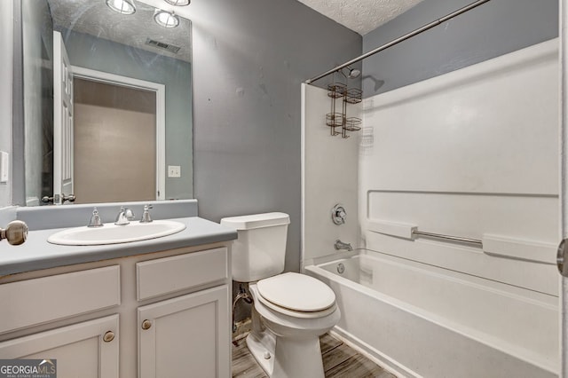 full bathroom with hardwood / wood-style flooring, shower / bath combination, vanity, a textured ceiling, and toilet