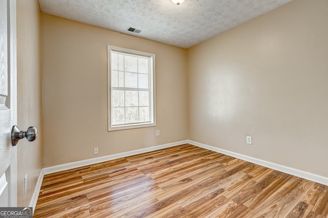 unfurnished room with light hardwood / wood-style floors and a textured ceiling