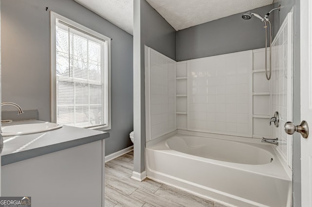 full bathroom featuring vanity, washtub / shower combination, a textured ceiling, and toilet