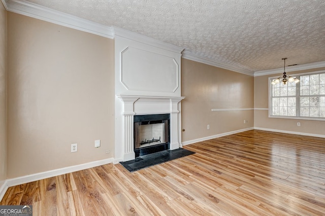 unfurnished living room featuring a notable chandelier, light hardwood / wood-style flooring, ornamental molding, and a large fireplace