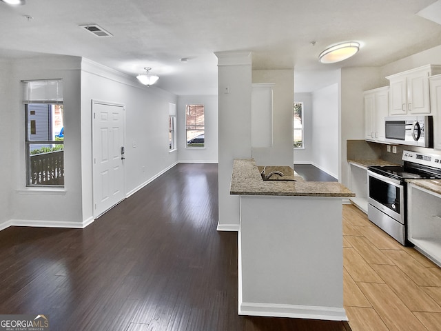 kitchen featuring stone countertops, wood-type flooring, stainless steel appliances, and white cabinetry