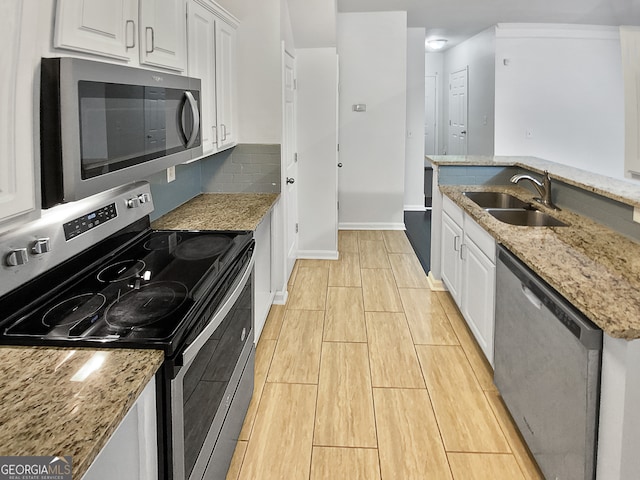 kitchen with appliances with stainless steel finishes, white cabinetry, sink, and light stone countertops