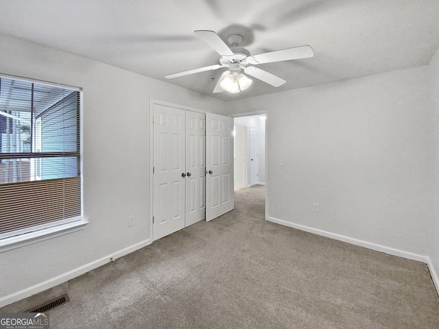 unfurnished bedroom featuring light colored carpet, ceiling fan, and a closet