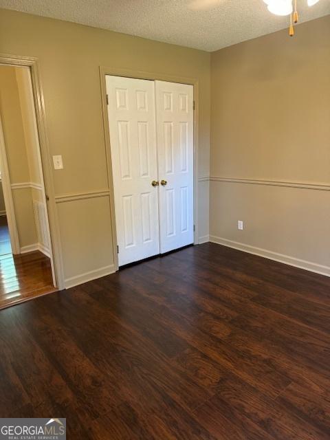 263 Hardin Rd SW, Plainville, GA 30733 - unfurnished bedroom featuring a textured ceiling, baseboards, dark wood-style floors, and a closet