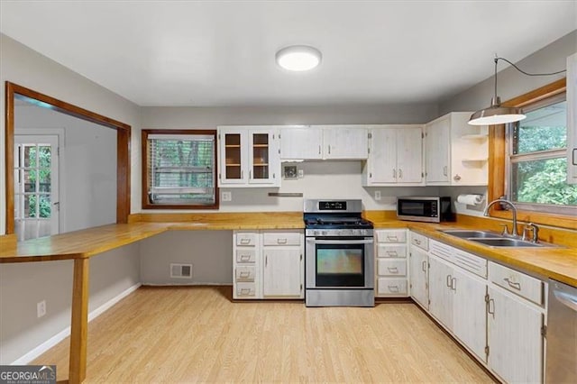 kitchen featuring stainless steel appliances, sink, white cabinets, and light hardwood / wood-style floors