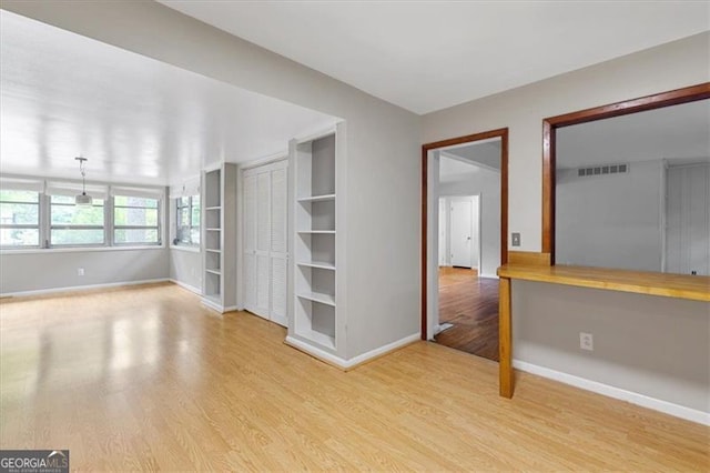 empty room with built in desk and light hardwood / wood-style floors