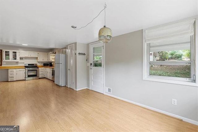 kitchen with light wood-type flooring, pendant lighting, white cabinetry, and stainless steel appliances