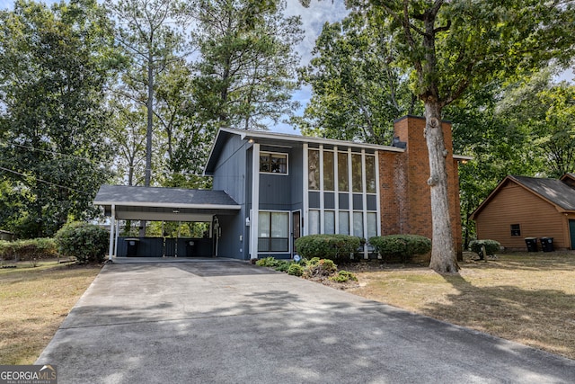 view of property featuring a front lawn, a carport, and a sunroom