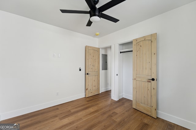 unfurnished bedroom with wood-type flooring, electric panel, ceiling fan, and a closet