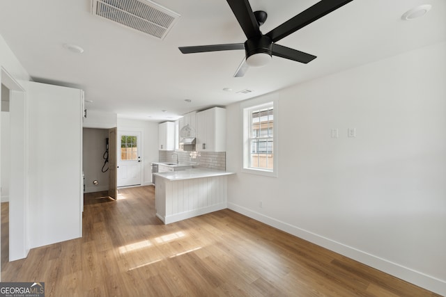 kitchen with a wealth of natural light, kitchen peninsula, sink, and white cabinets