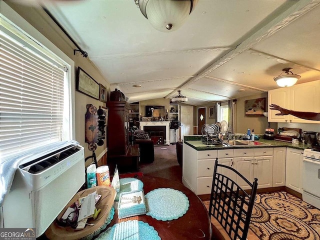 kitchen featuring white range, sink, carpet, vaulted ceiling, and white cabinets