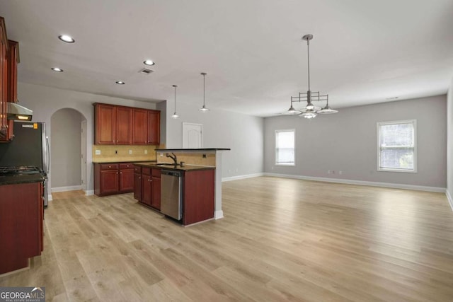 kitchen with backsplash, light hardwood / wood-style flooring, appliances with stainless steel finishes, an island with sink, and pendant lighting