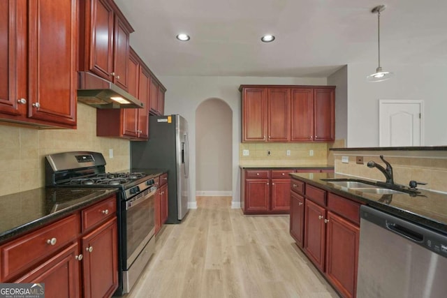 kitchen with light hardwood / wood-style floors, hanging light fixtures, stainless steel appliances, sink, and decorative backsplash