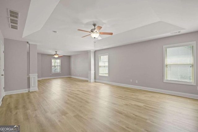 unfurnished living room with plenty of natural light, ceiling fan, ornate columns, and light hardwood / wood-style floors