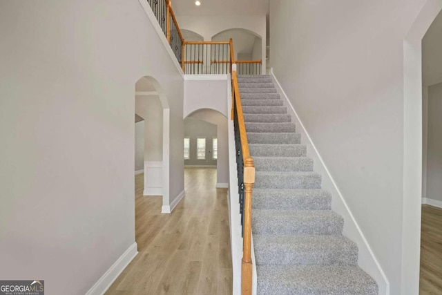 staircase featuring a high ceiling and hardwood / wood-style floors