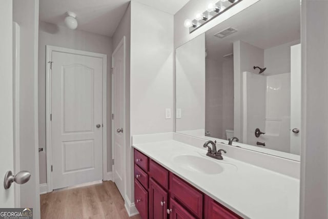 bathroom with vanity, toilet, wood-type flooring, and a shower