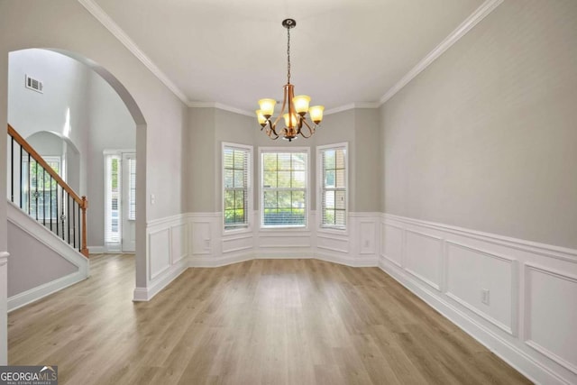 empty room with light hardwood / wood-style flooring, a chandelier, and ornamental molding