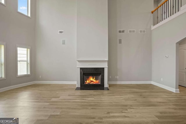 unfurnished living room featuring a high end fireplace, a wealth of natural light, and light hardwood / wood-style floors