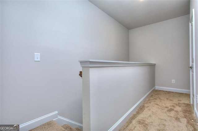 hall with baseboards, carpet floors, vaulted ceiling, and an upstairs landing