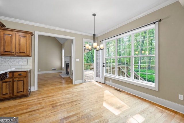 kitchen with ornamental molding, light hardwood / wood-style flooring, a notable chandelier, and tasteful backsplash