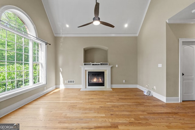 unfurnished living room with crown molding, plenty of natural light, ceiling fan, and light wood-type flooring