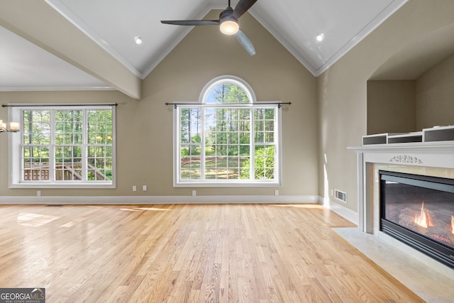 unfurnished living room featuring light wood-type flooring, ceiling fan, a fireplace, and a healthy amount of sunlight