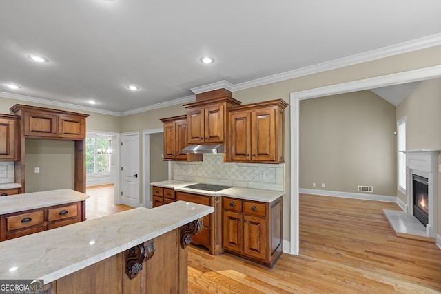 kitchen featuring light stone counters, decorative backsplash, ornamental molding, and light hardwood / wood-style flooring