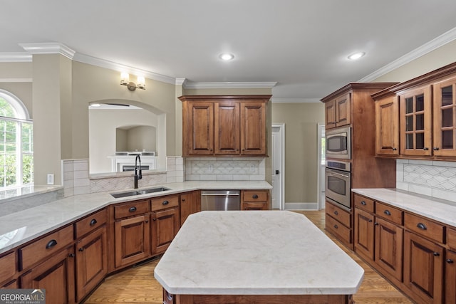 kitchen with light wood-type flooring, stainless steel appliances, a center island, and sink