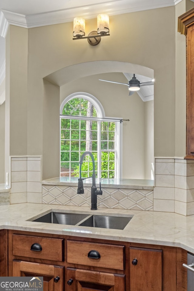 kitchen featuring ceiling fan with notable chandelier, light stone countertops, and decorative backsplash