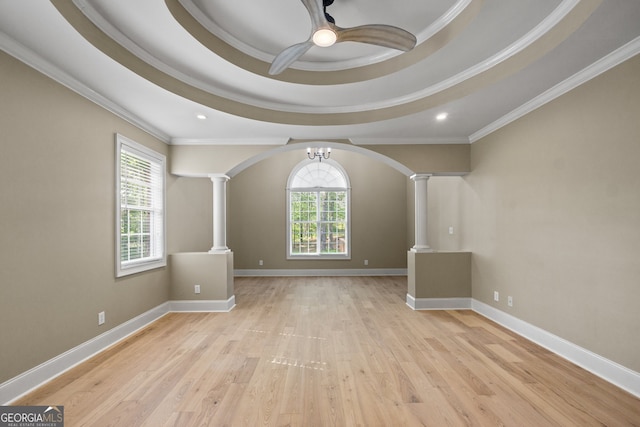 spare room featuring light hardwood / wood-style flooring, decorative columns, ornamental molding, and a healthy amount of sunlight