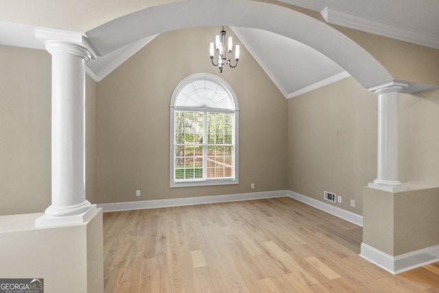 spare room with lofted ceiling, decorative columns, an inviting chandelier, and light hardwood / wood-style flooring