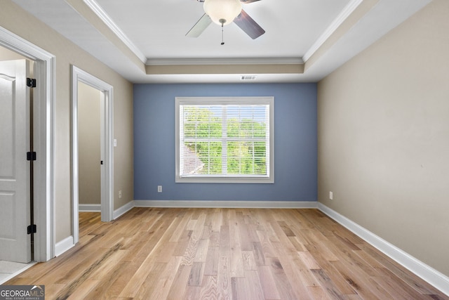 spare room with a tray ceiling, ceiling fan, light hardwood / wood-style floors, and crown molding