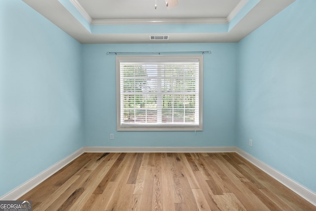 spare room featuring ornamental molding, a tray ceiling, and light hardwood / wood-style floors