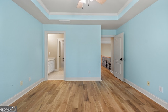 unfurnished bedroom featuring light wood-type flooring, crown molding, a tray ceiling, and ceiling fan